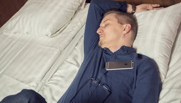 Kuva miehestä nukkumassa hotellin sängyllä