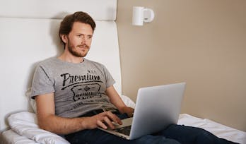 Mies istuu sängyllä läppäri sylissään Lönnrotin kadun Omena-hotellin uudessa Single-huoneessa.
