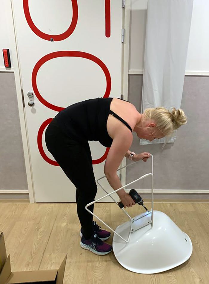 Omenan operatiivinen päällikkö ruuvaa jalat tuoliin Vaasan Omena-hotellin käytävällä.